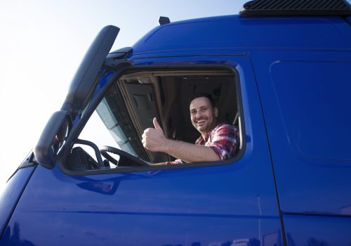 Truck driver showing thumbs up through cabin window.